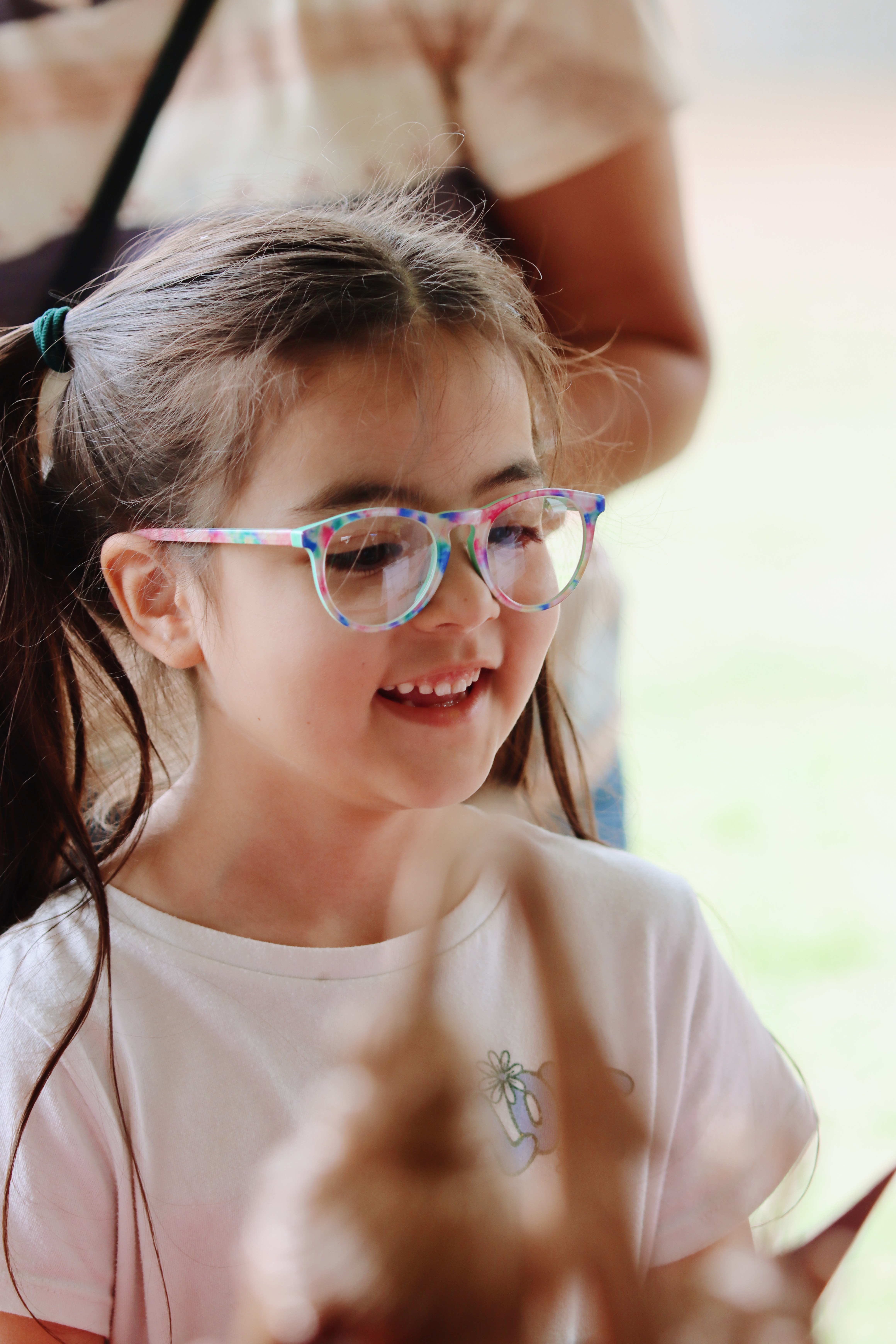 Girl with colorful glasses laughing at a craft activity