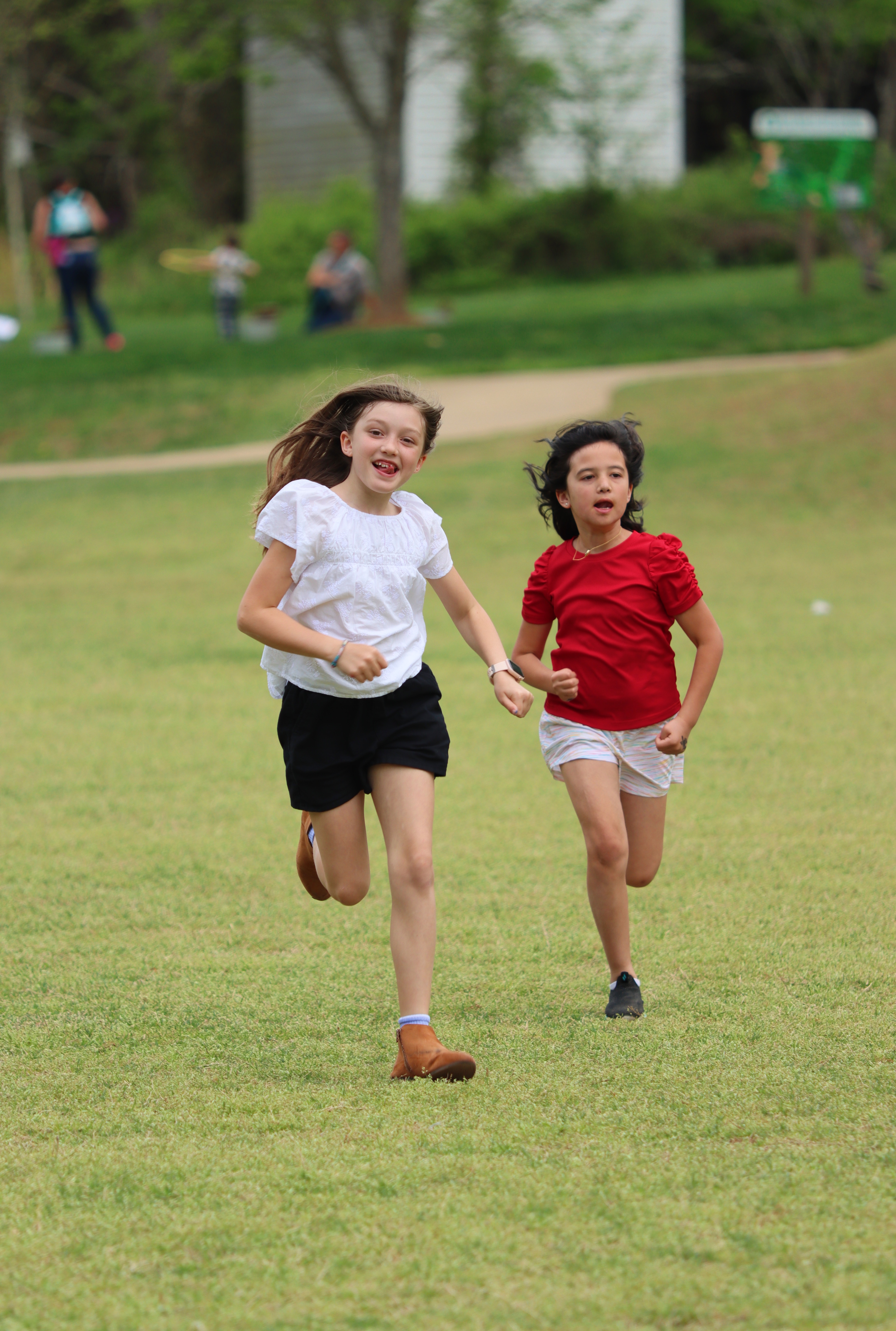 Two girls racing across the grass, hair flying in the wind
